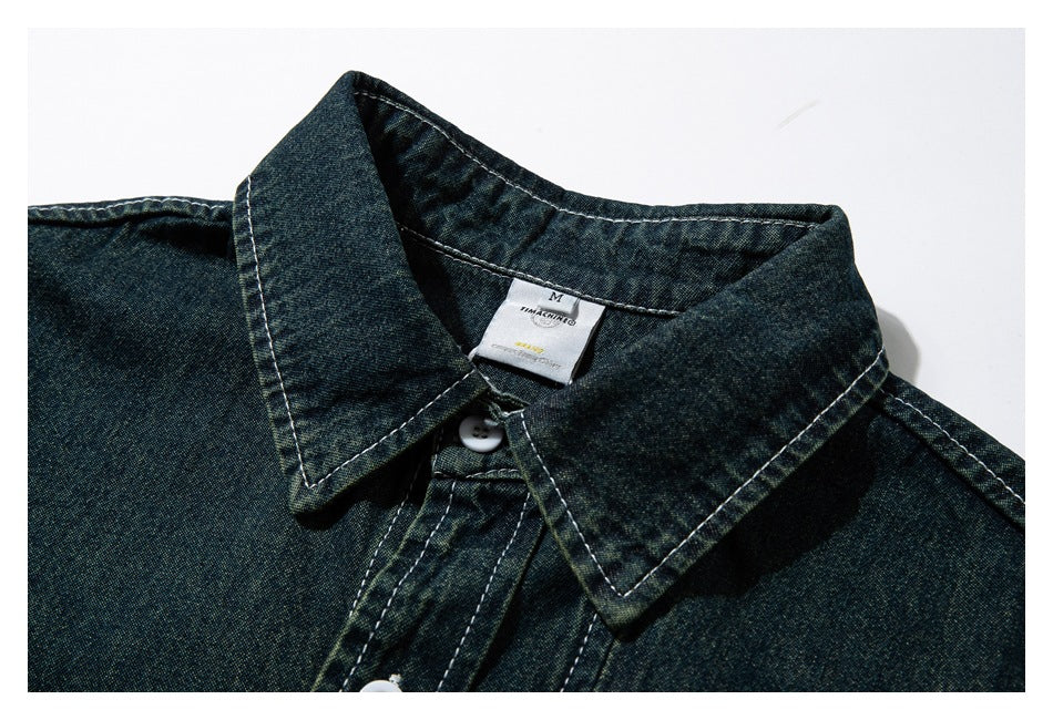 Close-up of the pointed collar and neck label on a dark blue-green shirt.