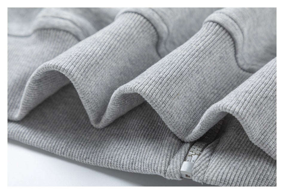 Close-up of the ribbed waistband and zipper edge on a heather gray hoodie.