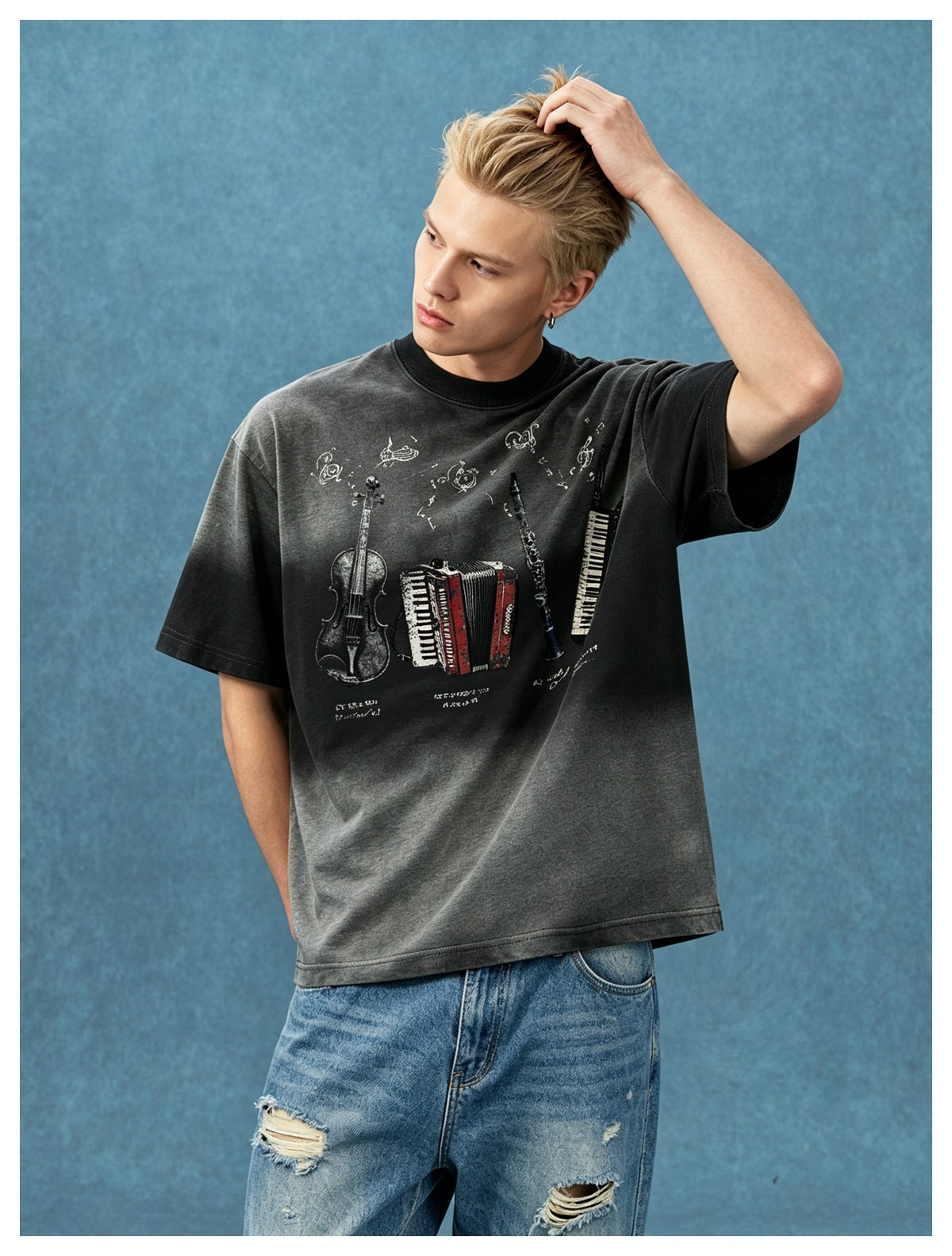 Model wearing a black faded oversized short-sleeve T-shirt with instrument graphic, paired with light ripped jeans