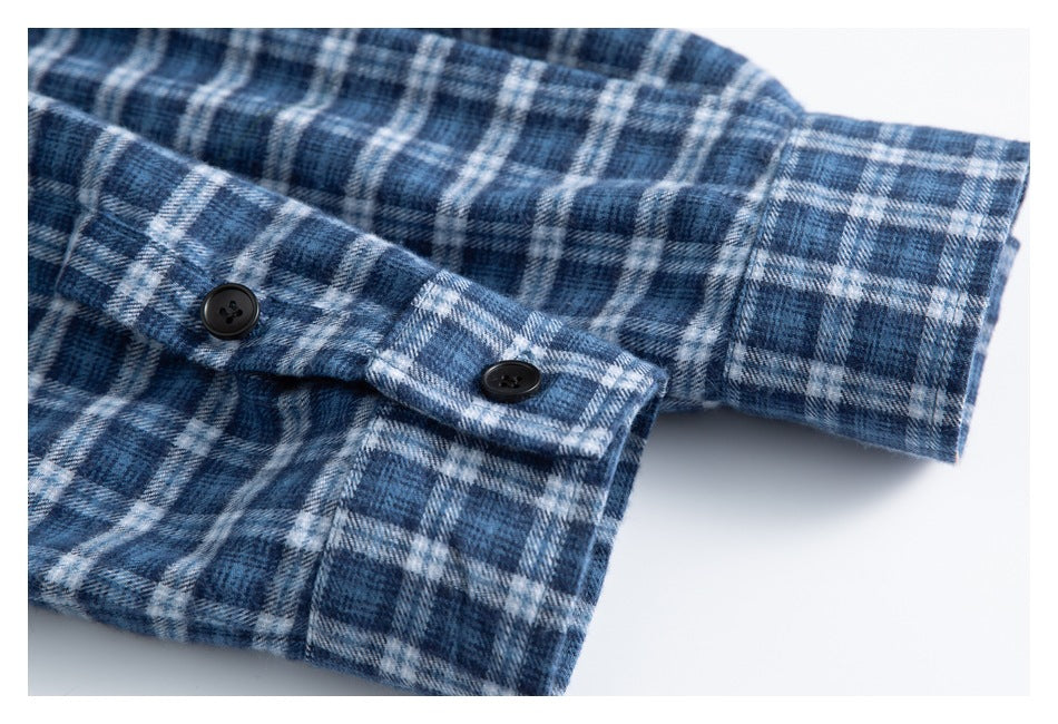 Close-up of a blue-and-white plaid shirt sleeve cuff with two black buttons.