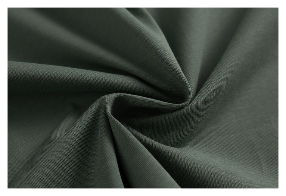 Macro view of sage-green fabric gathered into soft folds, showing its surface texture.