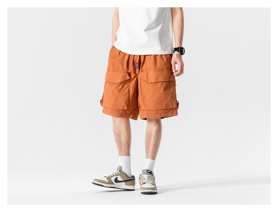 Model wearing caramel cargo shorts with a white tee and sneakers, front view cropped at the torso