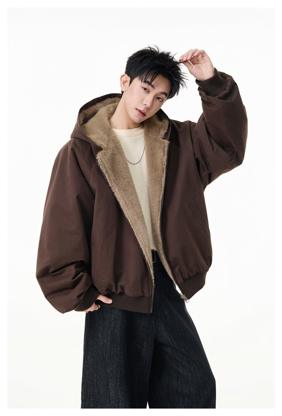 Model posing in an open dark brown hooded jacket with tan plush lining and oversized sleeves.