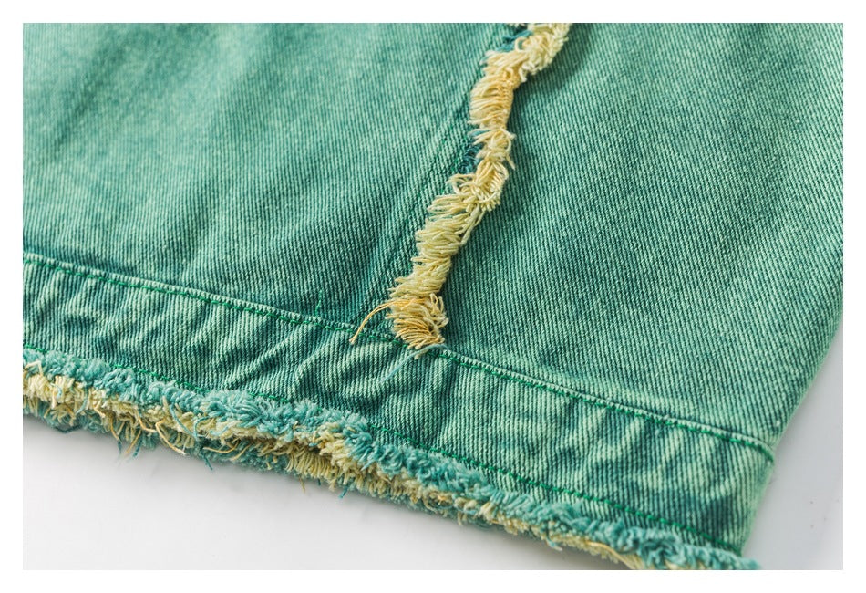 Close-up of the teal denim garment hem with yellow-and-teal frayed edging and a vertical seam.