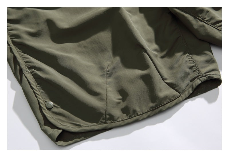 Close-up of the olive shorts' curved hem, stitching and small snap detail.