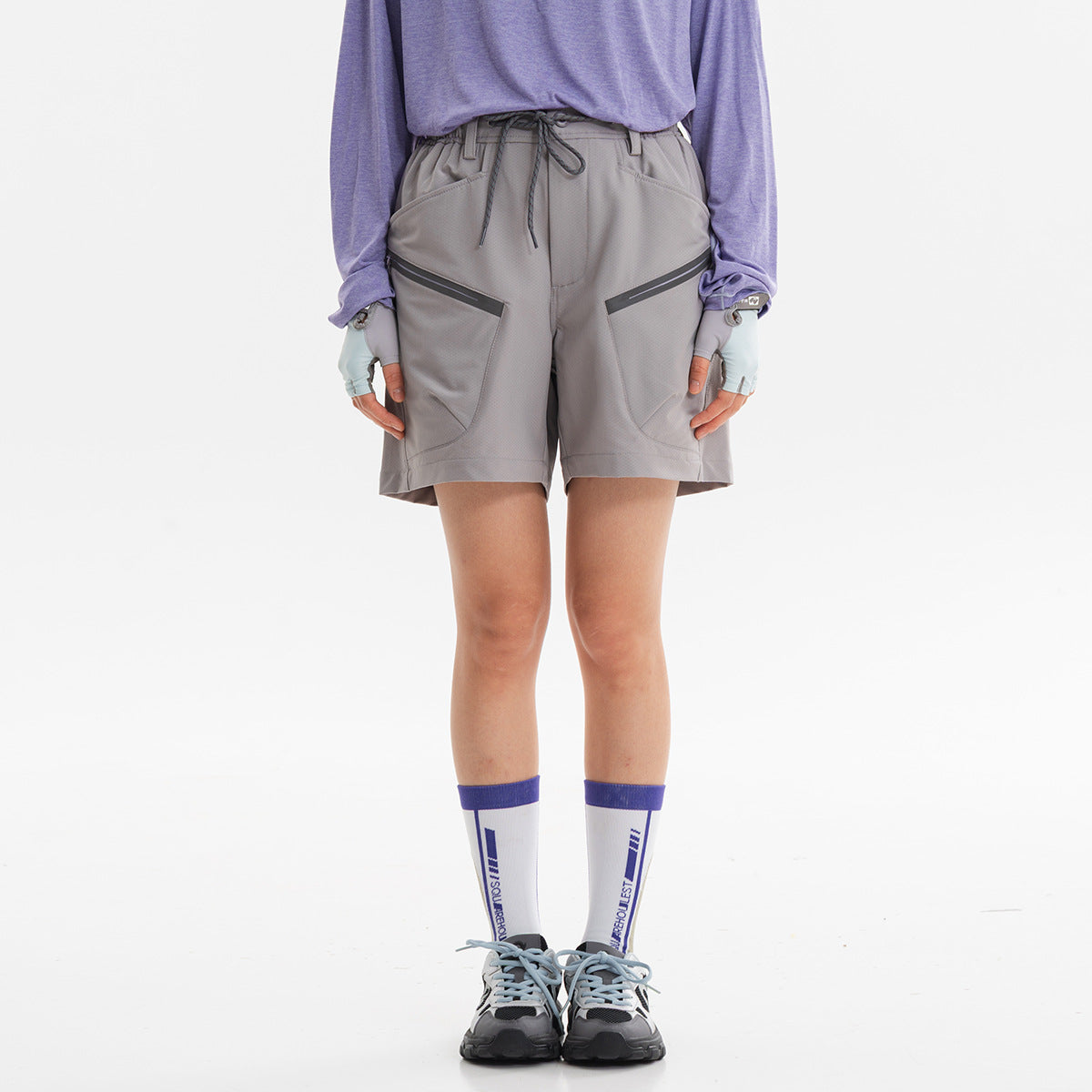Front view of a model wearing light gray drawstring shorts with two large angled zip pockets.