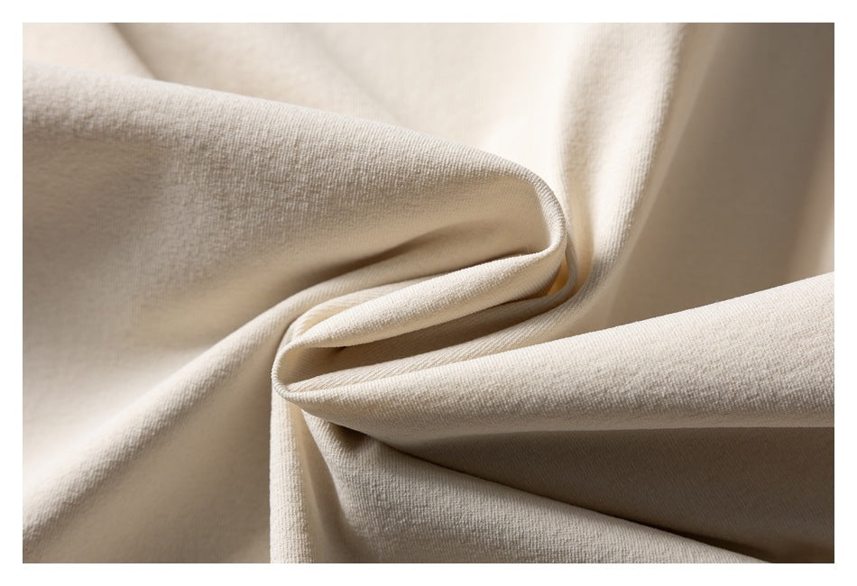 Close-up of cream-colored fabric arranged in soft folds, showing its fine textured surface.