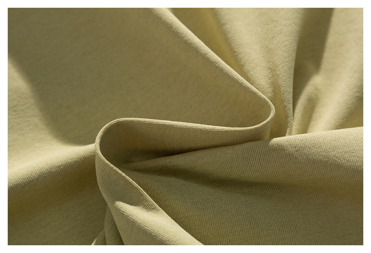 Close-up of plain beige fabric draped in folds, showing its fine ribbed texture.