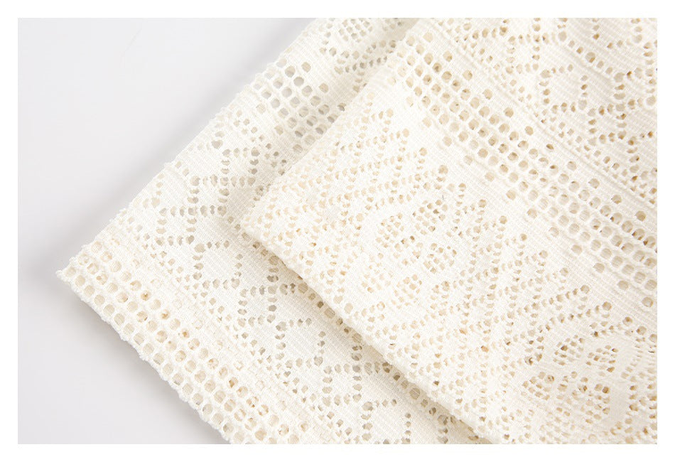 Close-up of layered ivory lace fabric with openwork floral and geometric patterns.