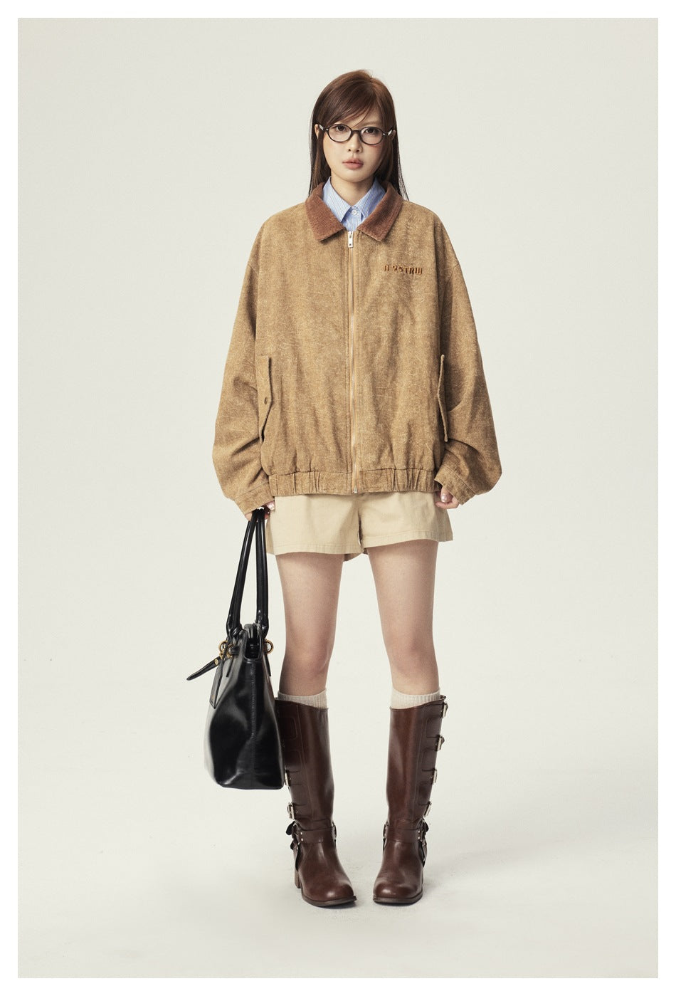 Front view of a model wearing a tan zip jacket with a brown collar and beige shorts.
