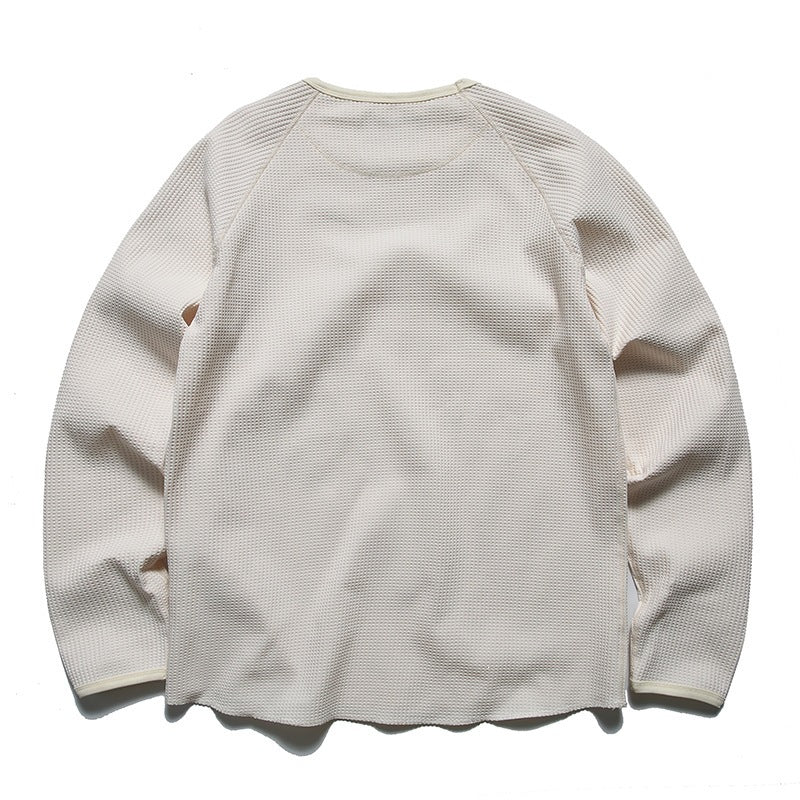 Back view of off-white waffle-knit long-sleeve top with raglan sleeves and raw curved hem