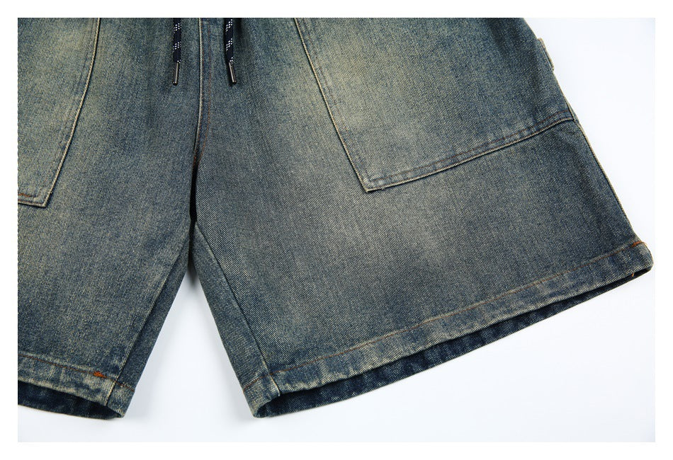Close-up of the wide leg openings and stitched hems on blue-gray denim shorts.