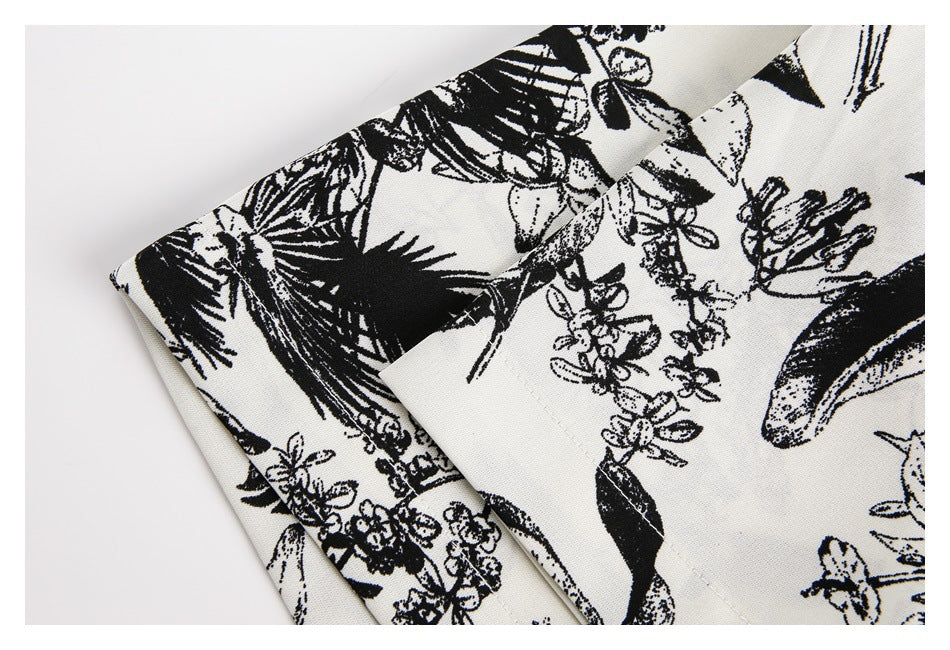 Close-up of the black botanical print and stitched edge on ivory garment fabric.