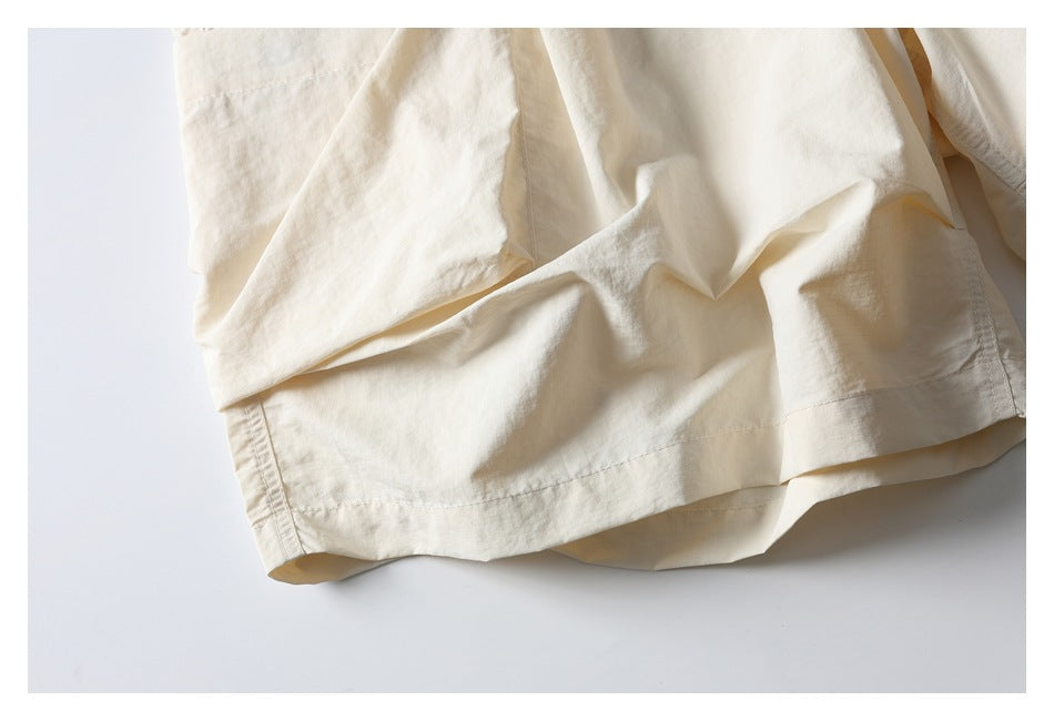 Close-up of the ivory shorts' leg panels and stitched hem, showing the relaxed cut and fabric folds.
