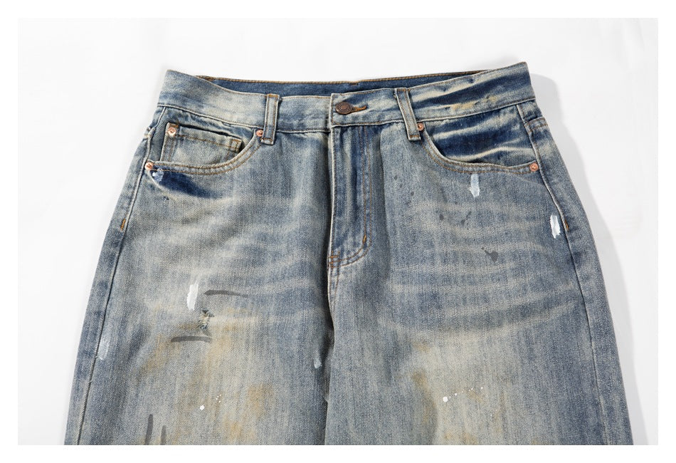 Close-up of the front waistband, button, belt loops, pockets and distressed marks on faded blue jeans.