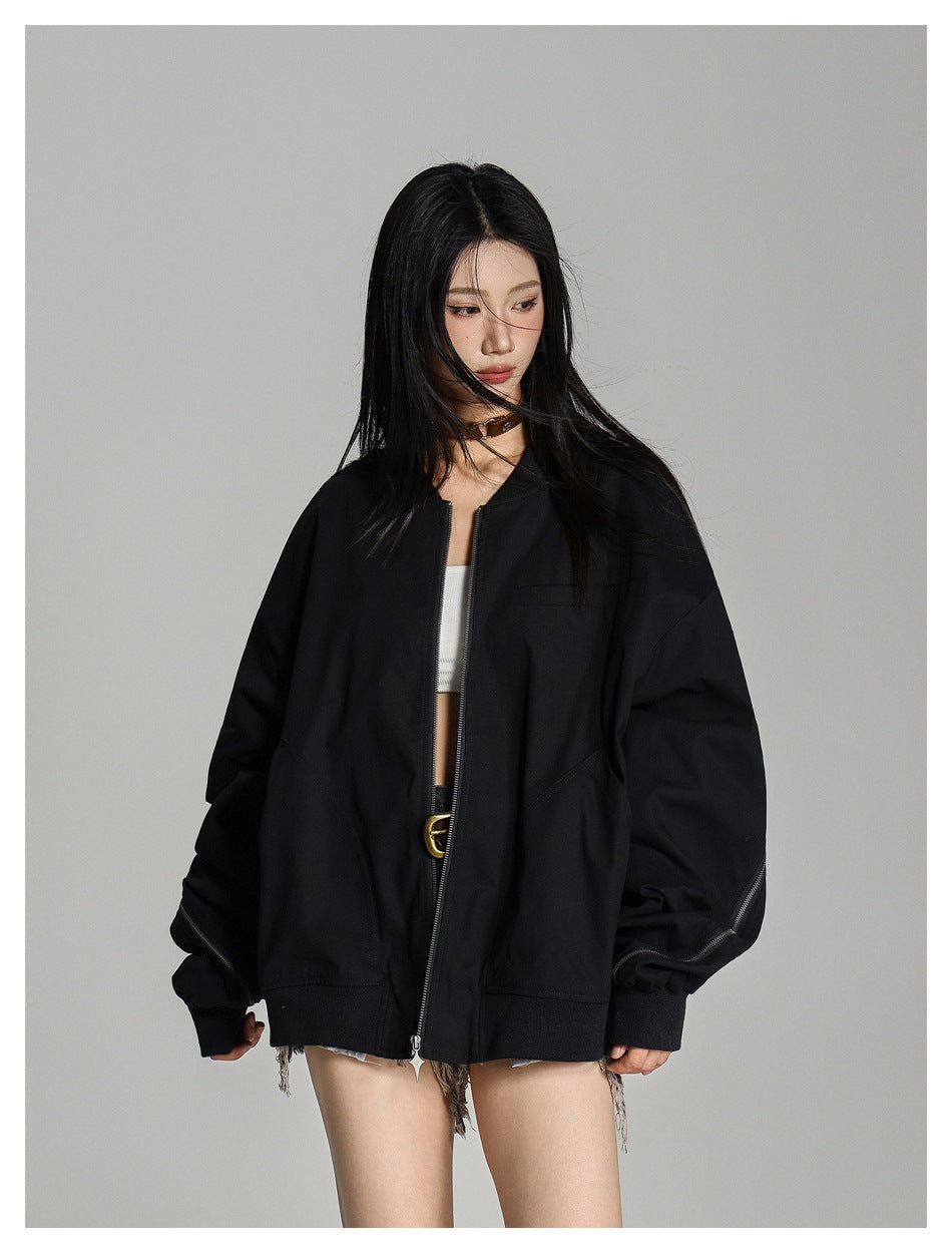 Model wearing an open oversized black bomber jacket with ribbed hem and zipper detail along the sleeve