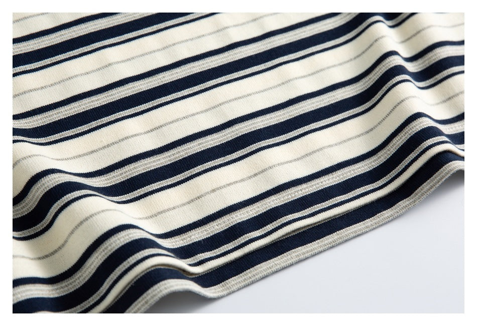 Close-up of the cream shirt's navy and gray horizontal stripes and curved lower hem.