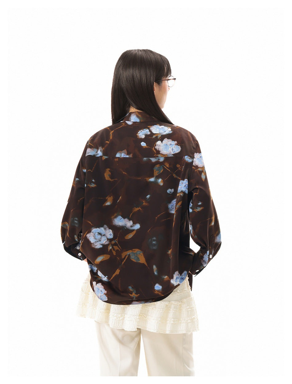 Close back view of a model wearing an oversized dark brown shirt with blue and pale floral print.