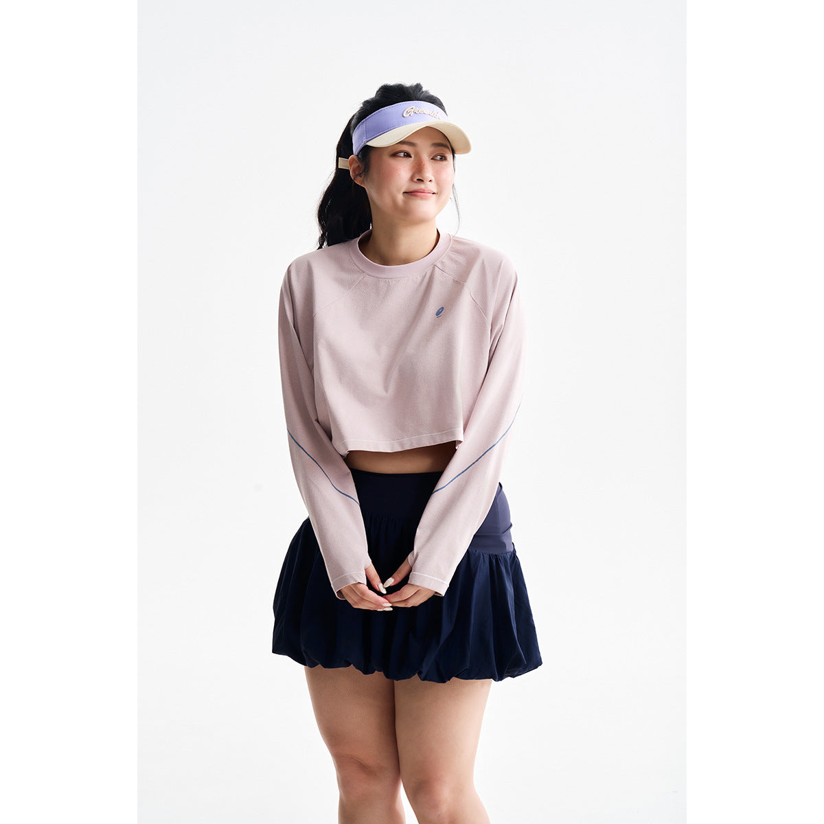 Model wearing a pale pink cropped long-sleeve top with blue sleeve piping and a navy bubble-hem skirt.