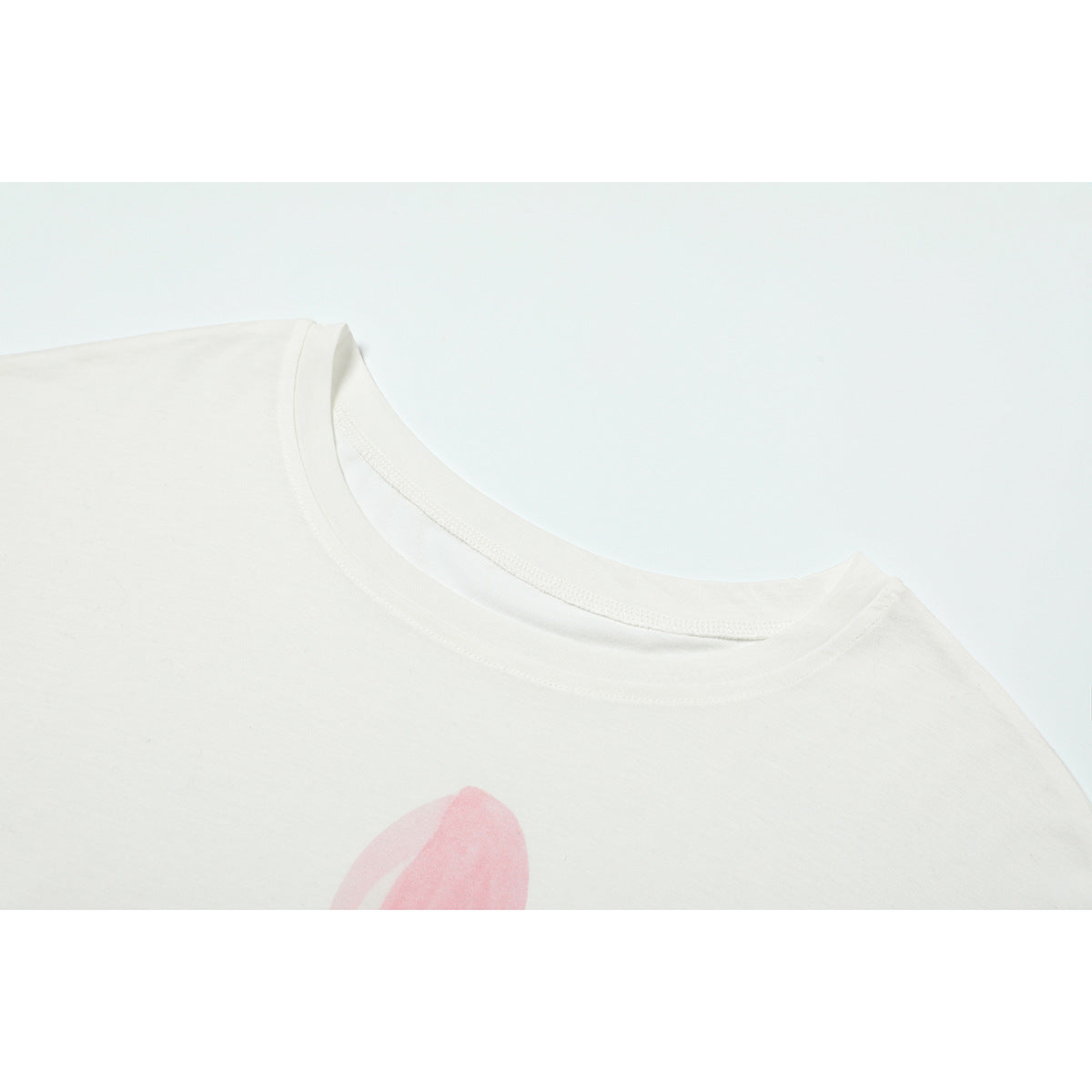 Close-up of a white T-shirt crew neckline with a small portion of pink artwork visible below.