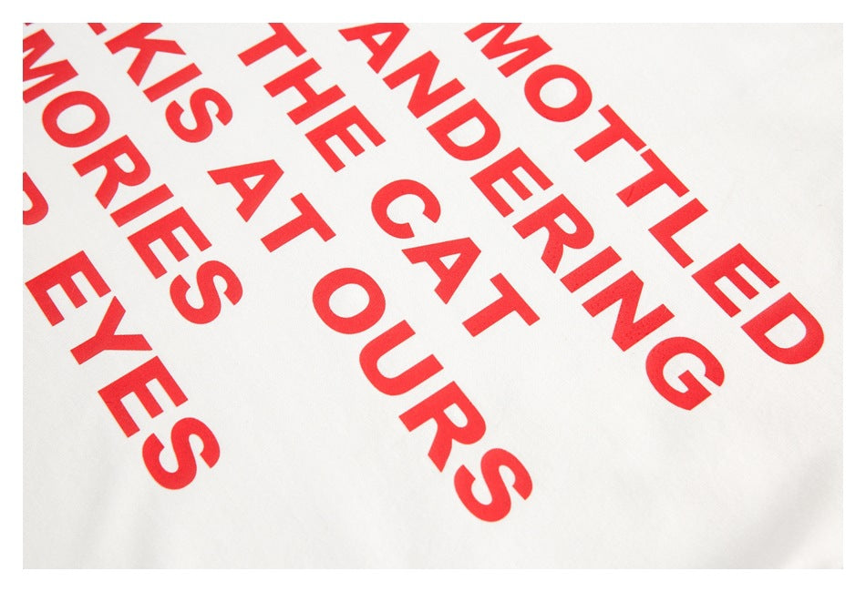 Close-up of large red lettering printed diagonally on white T-shirt fabric.