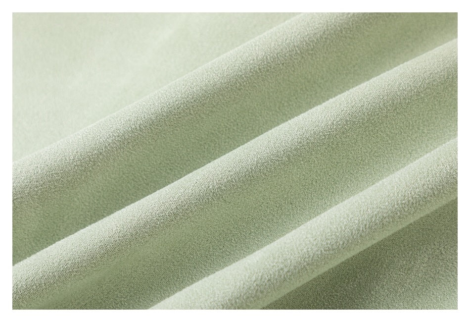 Extreme close-up of the pale sage-green garment's softly textured fabric.