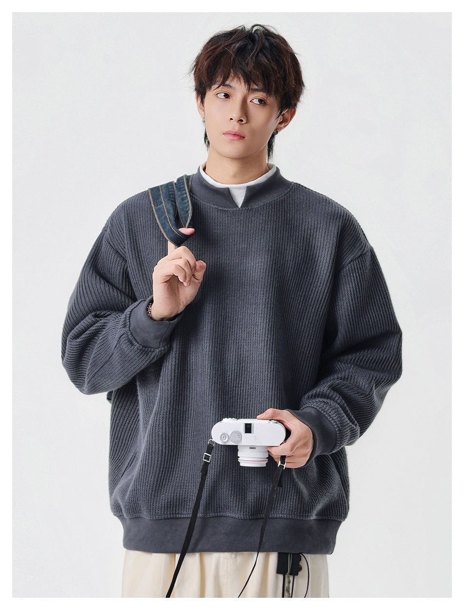 Model wearing a charcoal textured knit pullover with a split stand collar, ribbed cuffs and hem.