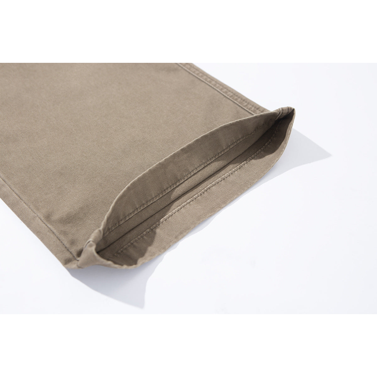 Close-up of a taupe pants leg with the hem folded back to show its stitching.
