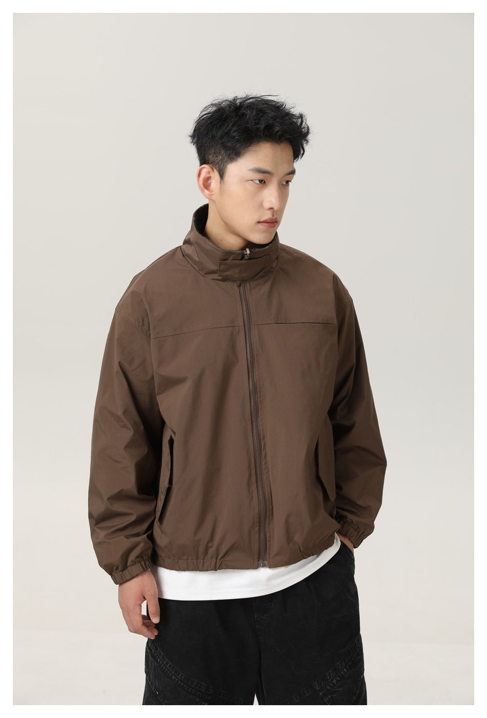 Model wears a zipped brown jacket with a stand collar and angled side pockets.