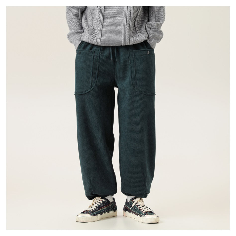 Front view of a model wearing dark teal wide-leg pants with large patch pockets and gathered ankle hems.