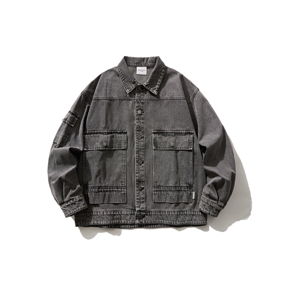Washed black denim jacket flat lay with large flap chest pockets, snap buttons and sleeve pocket