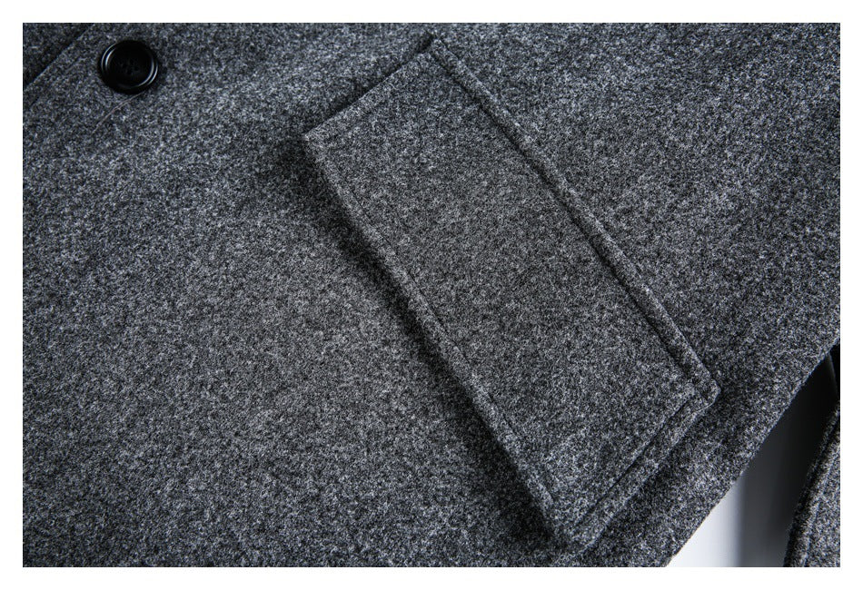 Close-up of a charcoal-gray flecked coat with a black button and rectangular pocket flap.