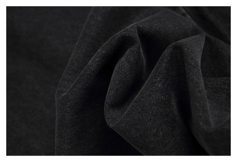Close-up of dark charcoal denim fabric draped into folds, showing its fine diagonal weave.