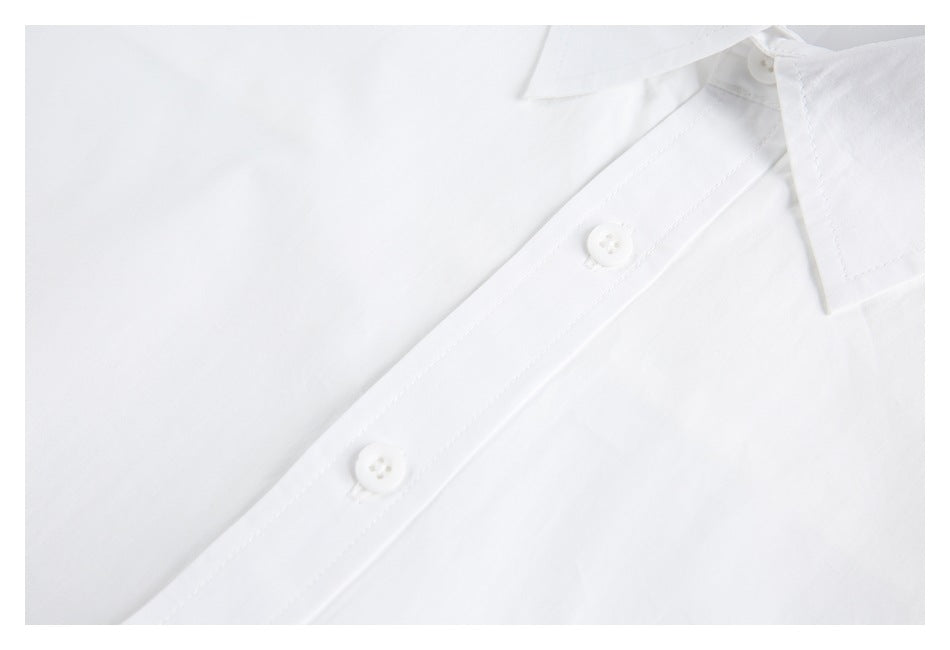 Close-up of a white shirt placket with two white buttons and part of the pointed collar.