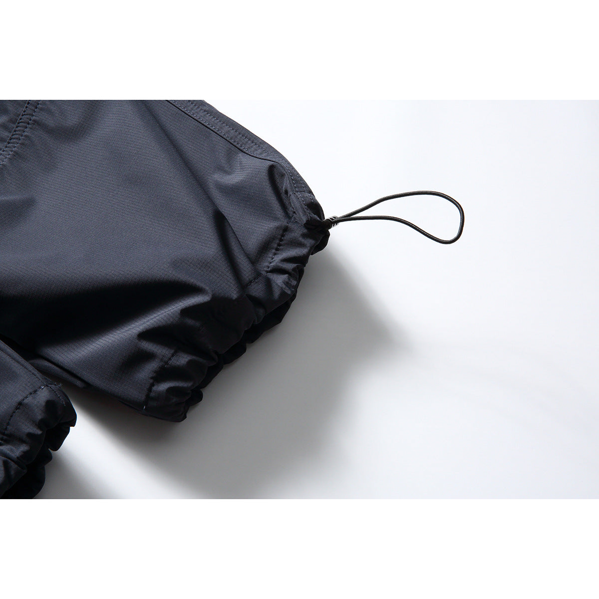 Close-up of dark navy pant cuff with gathered elastic and an adjustable loop drawcord.