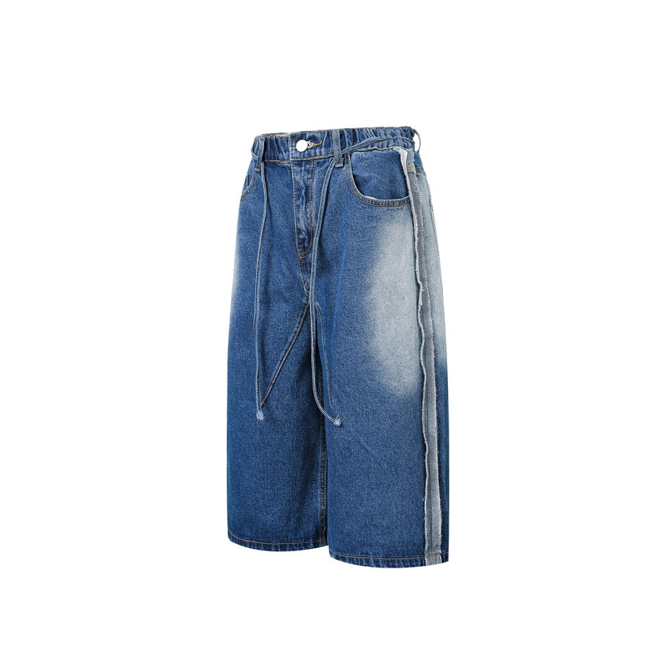 Front view of loose, wide-leg blue denim shorts with a button waist, front pockets, faded panels, and exposed side seams.