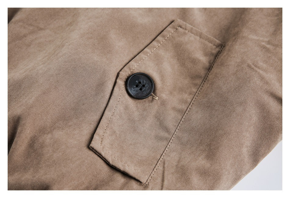 Close-up of a rectangular buttoned tab on a taupe coat.