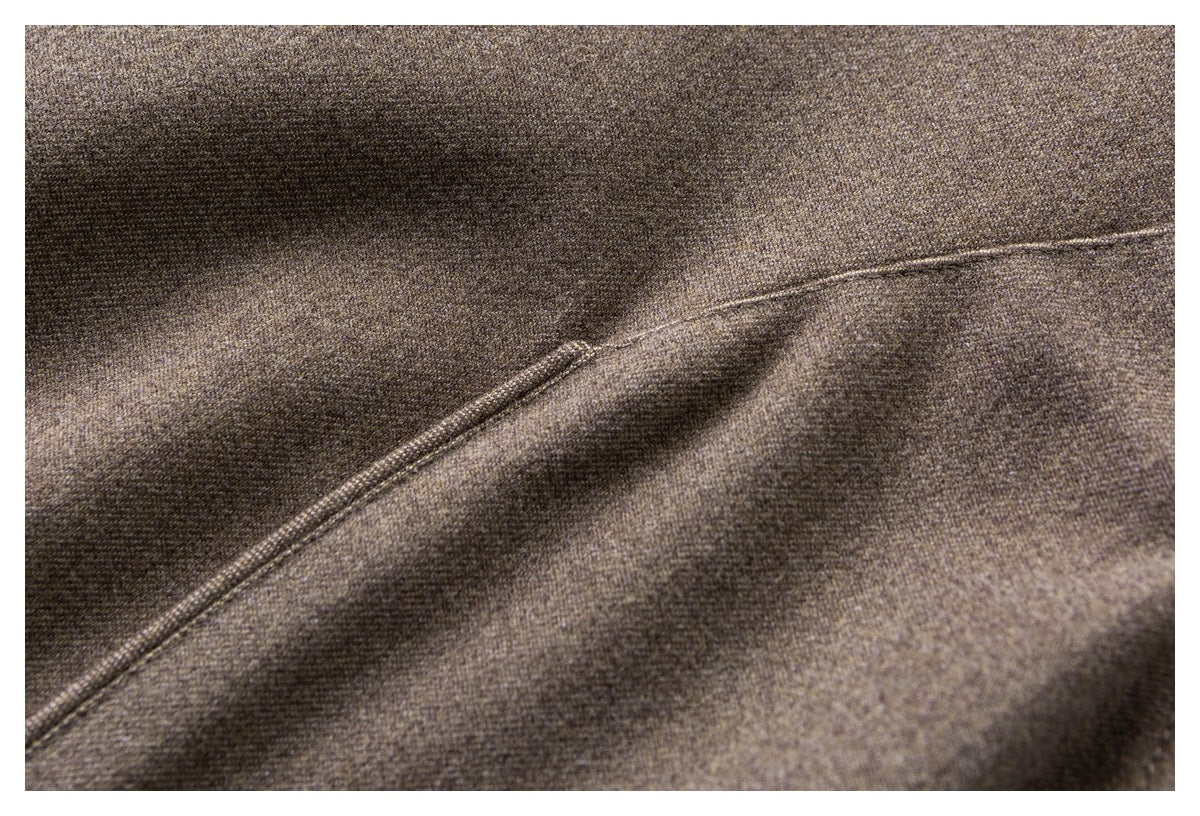 Close-up of a curved stitched seam on brown textured coat fabric.
