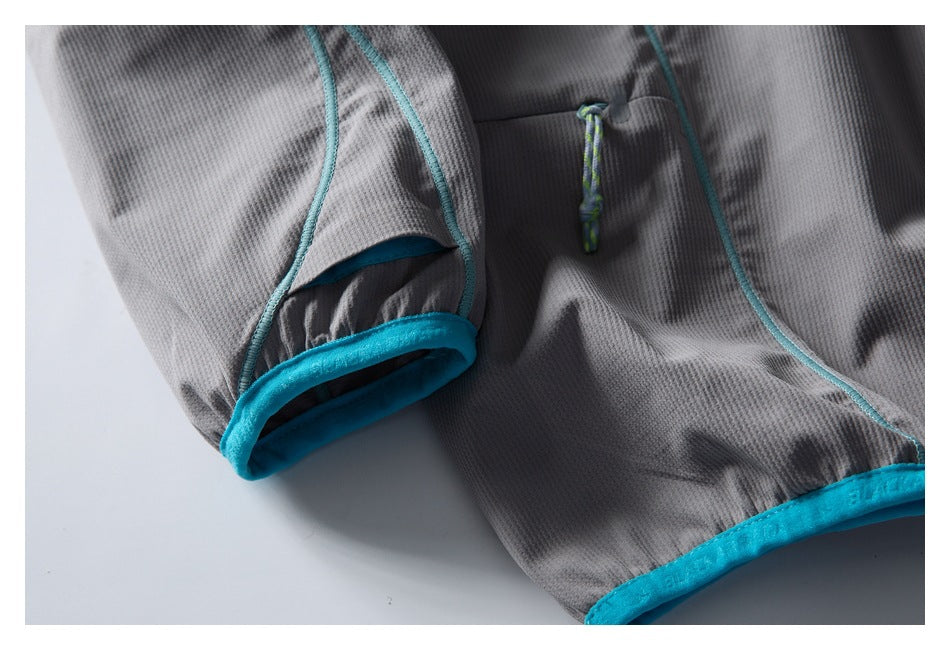 Close-up of the gray pullover’s turquoise-bound cuff and hem, curved piping, and small cord detail.