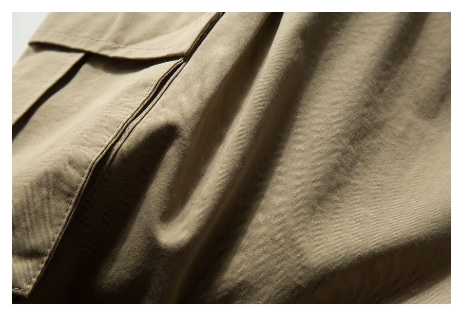 Close-up of khaki trousers showing a stitched pocket edge and fabric folds.
