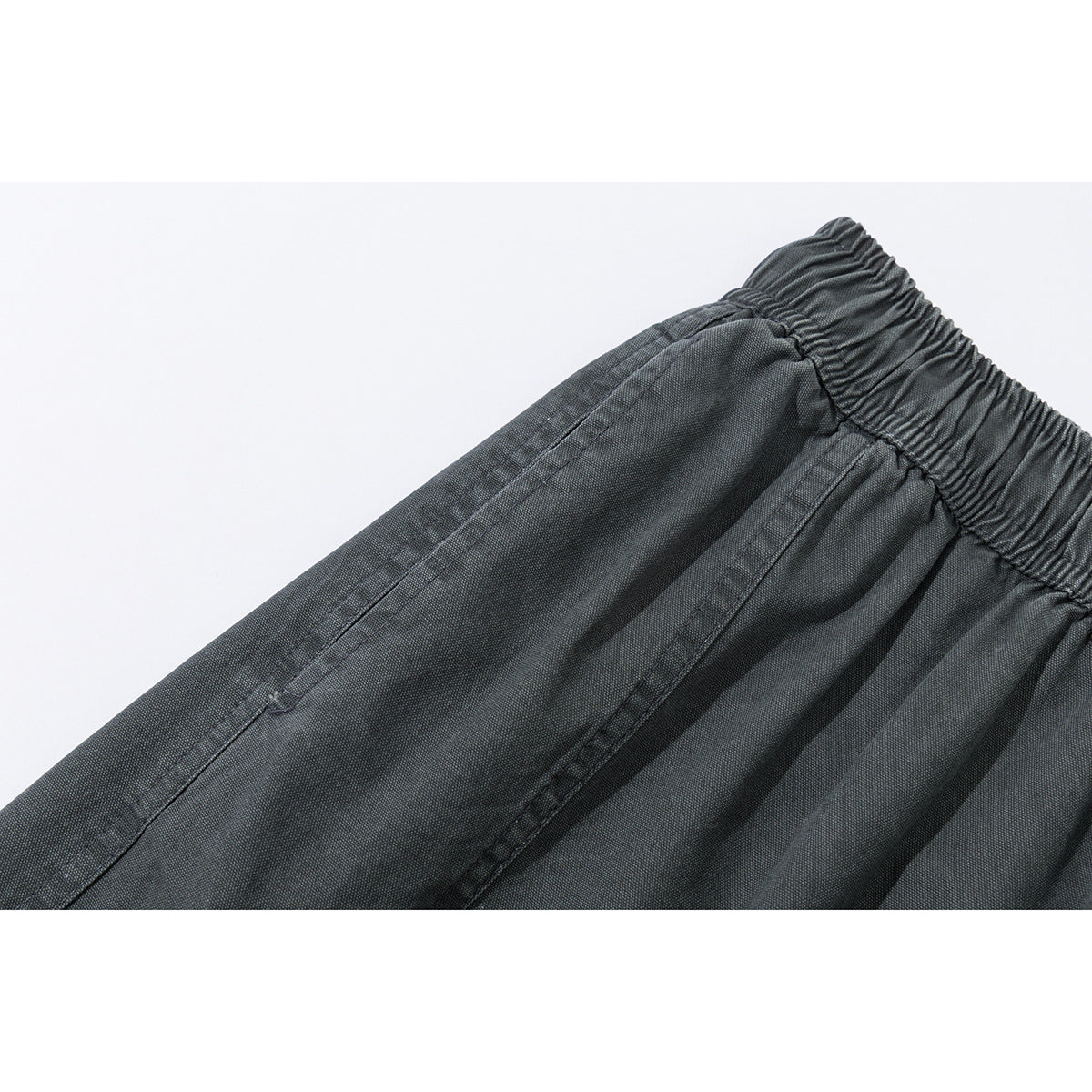 Close-up of charcoal shorts showing the gathered elastic waistband and stitched front panel.