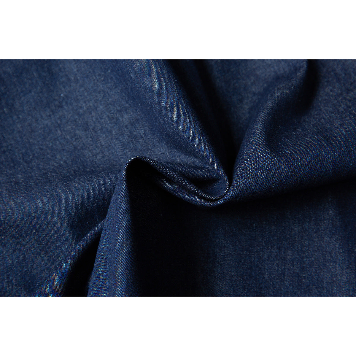 Macro view of dark indigo fabric folded to show its fine woven texture.