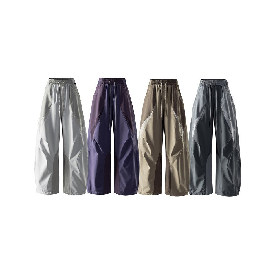 Four pairs of loose drawstring pants displayed side by side in light gray, purple, taupe and charcoal.