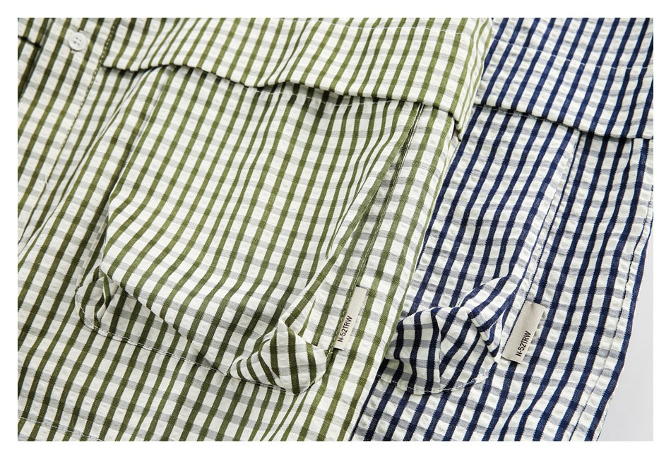 Close-up of two shirts in white with olive-green and navy striped check patterns.