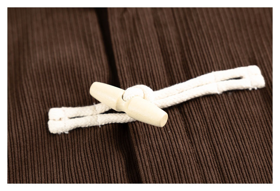 Close-up of a cream toggle and loop closure against the brown ribbed jacket front.
