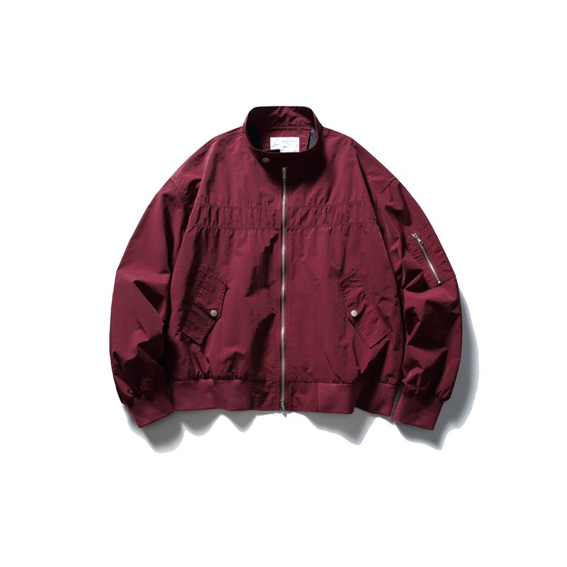 Dark red stand-collar zip jacket flat lay with flap pockets, sleeve zip pocket and ribbed cuffs and hem