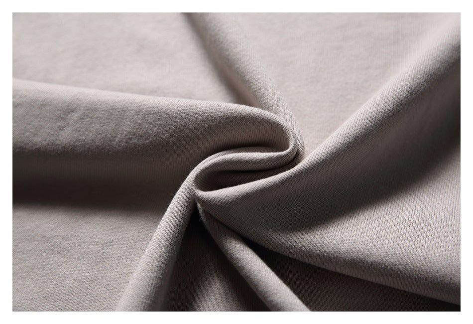 Close-up of taupe-gray fabric gathered into soft folds, showing its surface texture.