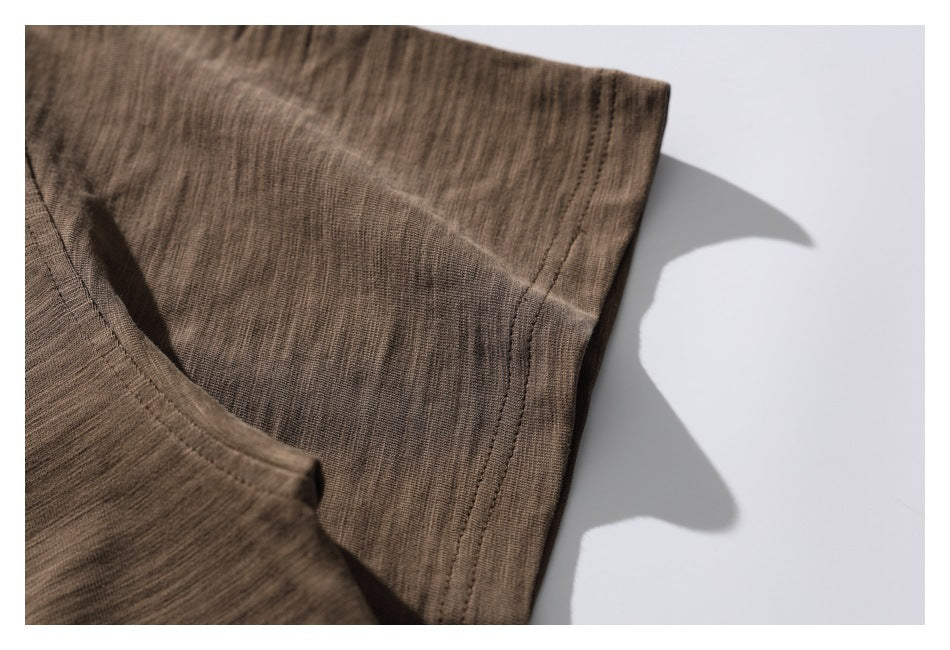 Close-up of a brown shirt sleeve edge with double stitching against a white background.