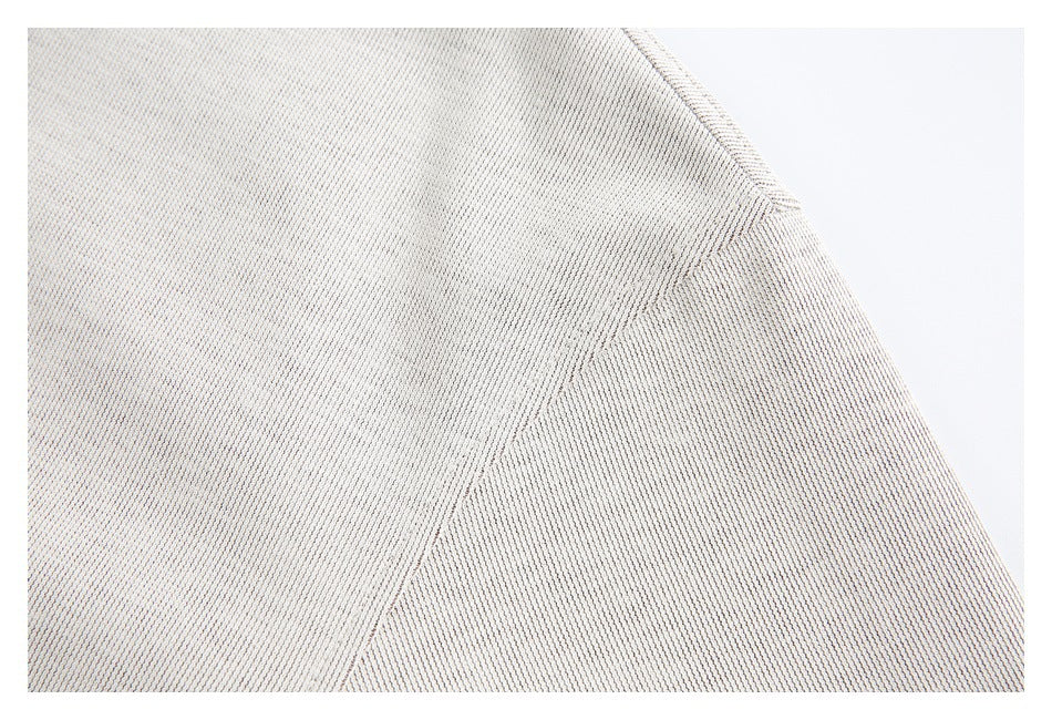 Close-up of cream textured fabric and a curved stitched seam.
