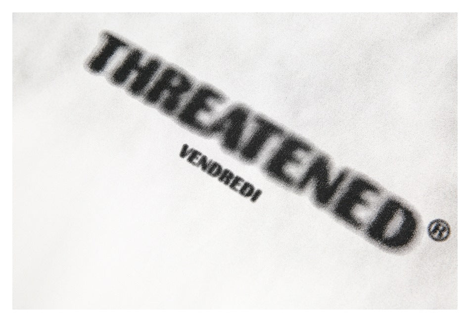 Close-up of black printed lettering and a smaller line of text on white T-shirt fabric.